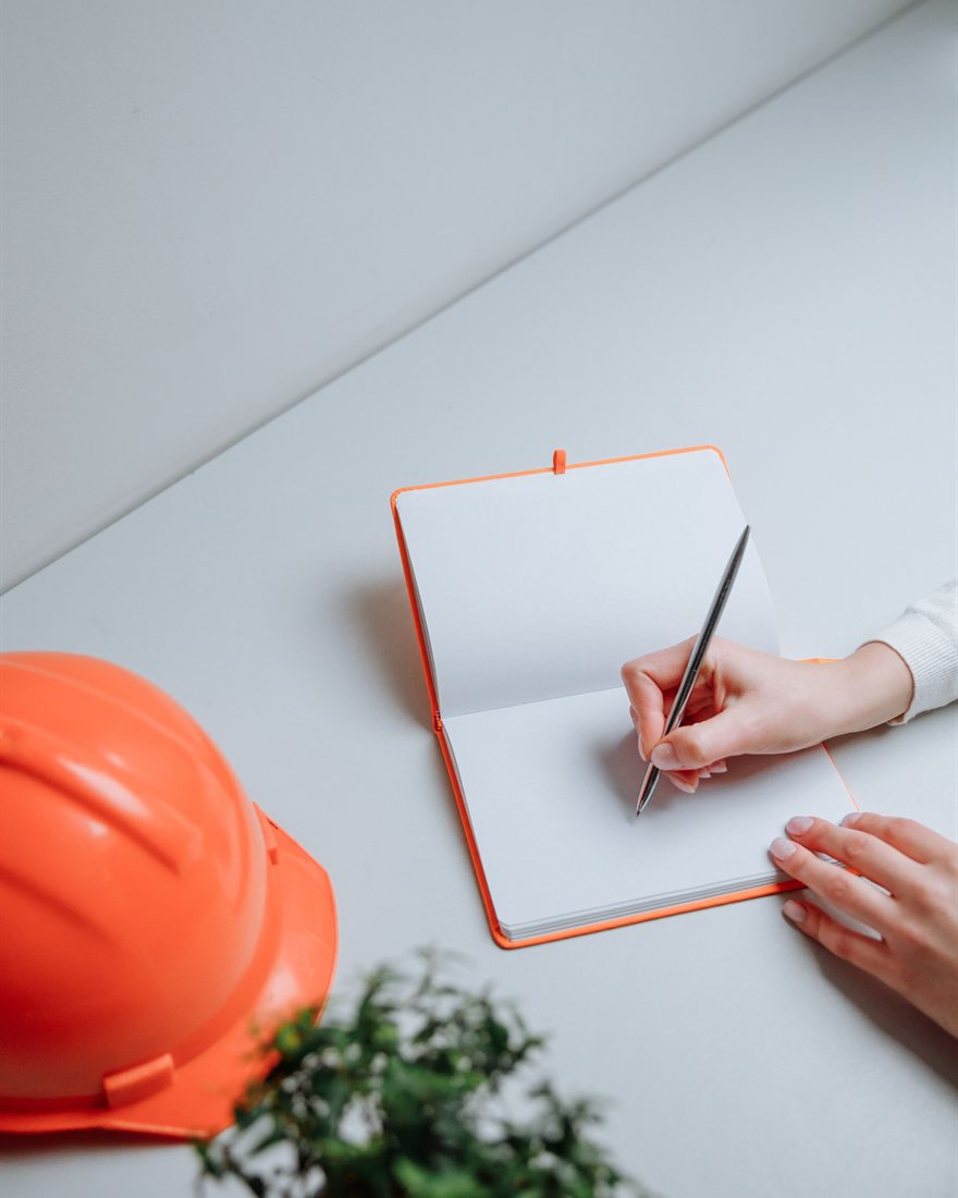 A hard hat beside an open notebook as a course plan is written up